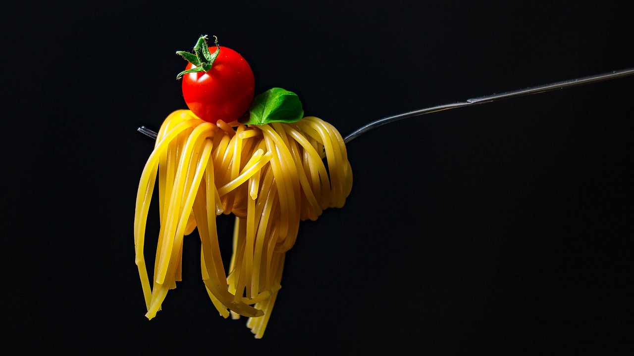 Piatto di pasta con salsa, verdure e formaggio, simbolo di una dieta equilibrata.
