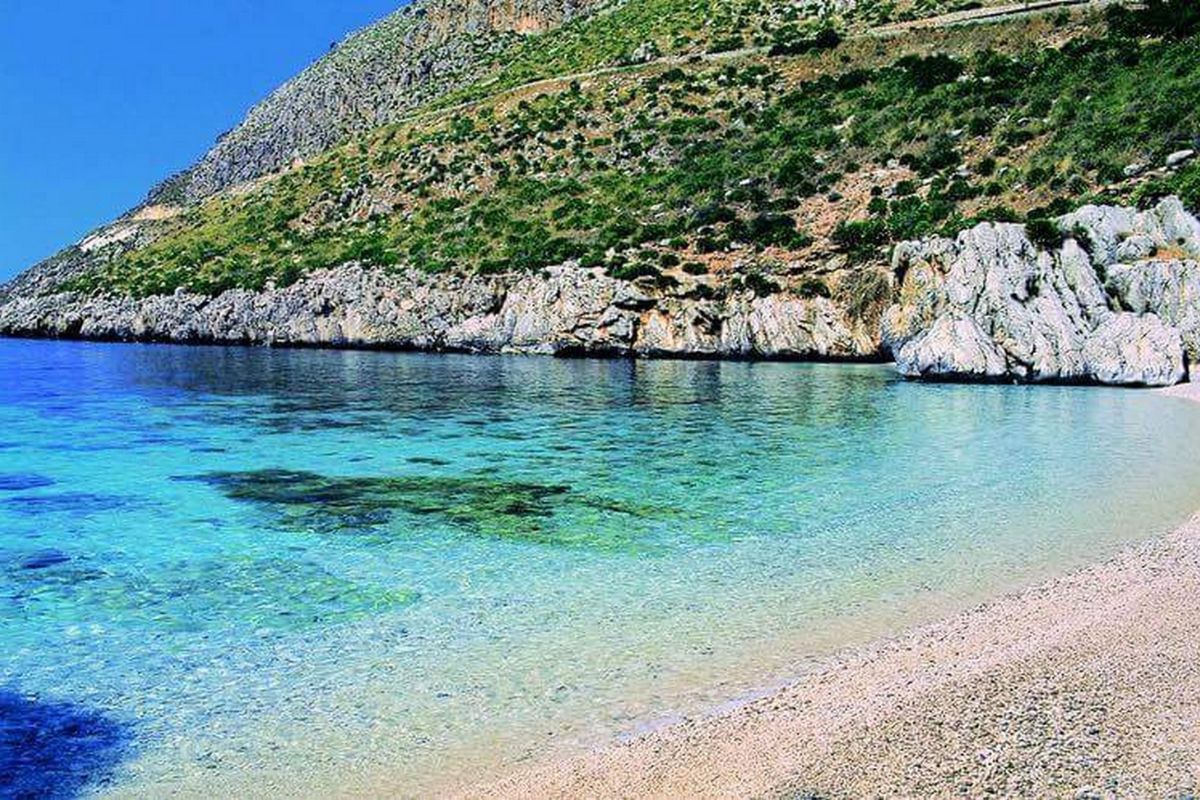 Cala Domestica, spiaggia sarda con miniere abbandonate sullo sfondo, ideale per esplorazioni e relax.
