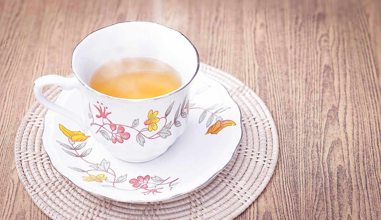 Tazza di tè caldo su un tavolo, con foglie di tè e limone, simbolo di benessere e perdita di peso.