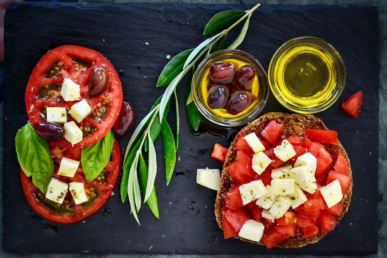 Immagine di piatti tipici della dieta mediterranea con frutta, verdura e olio d'oliva, simbolo di una sana alimentazione.